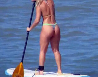 Infatuating butt in g-string bathing suit on surfboard.